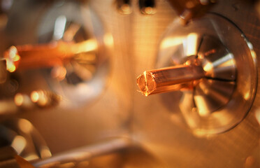 copper square bar protruding from the chuck during processing in a turning machine, red colors