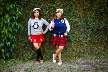 Fototapeta premium Two women in green garden and ivy with sunlight. Asian girls happy to go outside.