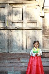 Asian children smile in national costumes. Little girl kid with Korean hanbok dress on wooden board background.