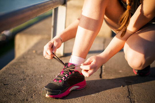 A girl ties her sneaker laces before going for a run.