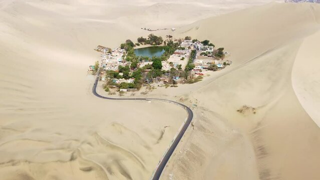Huacachina, Peru: Aerial drone footage of the stunning Huacachina oasis in the sand desert near Ica in Peru in south America. Shot with a downward and tilt up motion. 