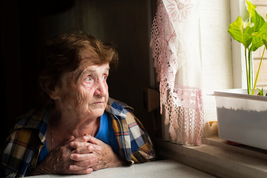 A lonely old woman stares doomfully out the window.