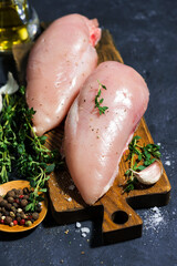 raw chicken breast and fresh thyme on a cutting board, closeup top view