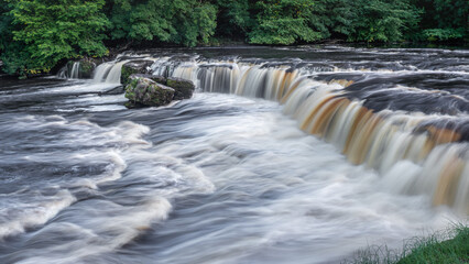 Aysgarth Falls are a triple flight of waterfalls, surrounded by forest carved out by the River Ure on its descent through Wensleydale in the Yorkshire Dales