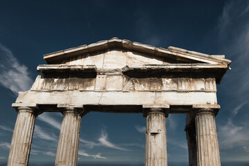Front view of a Greek ancient arch. Remains of an old temple stand against a deep blue sky with...