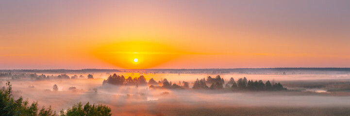 Amazing Sunrise Sunset Over Misty Landscape. Scenic View Of Foggy Morning Sky With Rising Sun Above Misty Forest And River. Early Summer Nature Of Eastern Europe. Panorama.