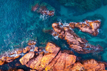 Naklejka na ściany i meble Summer background with the orange rocks and the blue sea. Artistic background of the ocean coast. Summer conceptual background. Costa Brava, mediterranean, summer vacations, beach.