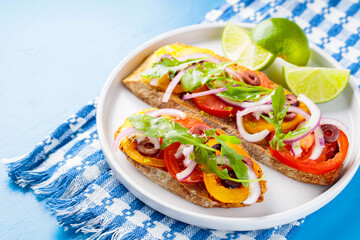 Traditional spanish tapas on a blue background. Healthy sandwiches with vegetables, greens, olives and lime. Vegetarian sandwiches on a white plate. Top view