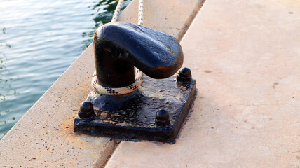 Mooring device for a yacht in a port made of metal for pulling a cable, black color. Denia, Spain