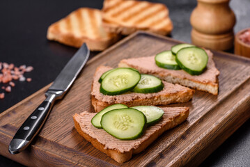 Delicious fresh sandwich with chicken liver pate with crispy toast, butter and cucumber