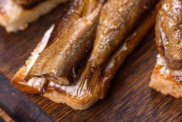 Delicious fresh sandwich with sprats with crispy toast, butter and cucumber
