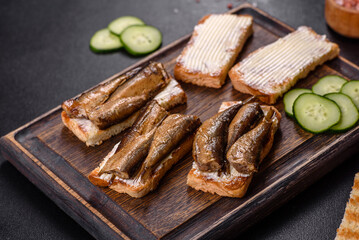 Delicious fresh sandwich with sprats with crispy toast, butter and cucumber