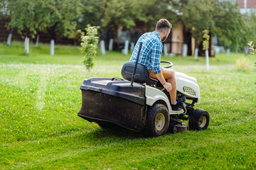 Portrait of professional lawn mower with worker cutting the grass in a garden