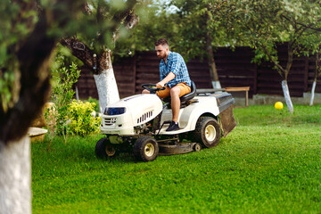 Portrait of gardener using a lawn mowing tractor for cutting grass. professional gardening details