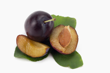 Whole and piece plums with leaves and seeds isolated on bright backgrounds. Close up view.