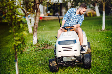 Landscaping details - portrait of gardener smiling and mowing lawn, cutting grass in garden