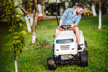 Fototapeta premium Landscaping details - portrait of gardener smiling and mowing lawn, cutting grass in garden