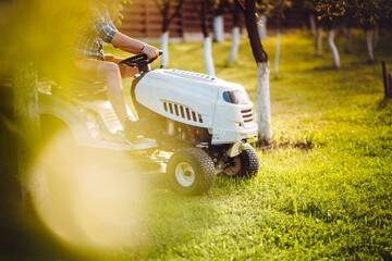 Close up details of lawn mowing tractor during sunset hour - obrazy, fototapety, plakaty