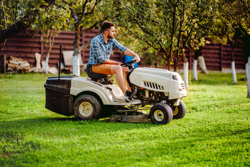 Fototapeta premium Industry details - portrait of gardener smiling and mowing lawn, cutting grass in garden
