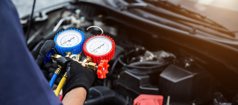 Close up hand of auto mechanic are to use measuring manifold gauge for filling car air conditioners. Concepts of fix and checking for repair service , Car service concept .
