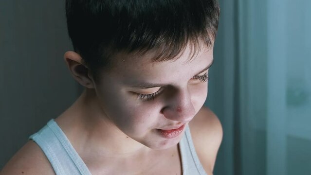 Face of a Guilty, Speaking Smiling Teenager with a Downcast Look. Side view. Conflict with parents, repentance, punishment, awareness of guilt. Behavior, emotion, reaction, dialogue. Childhood age.