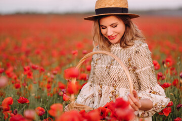 Fototapeta na wymiar a girl in a dress with a hat and with a basket in a field with poppies