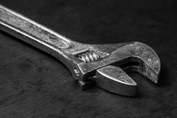 Old adjustable wrench on a black background. Black and white photograph of a working tool. old...
