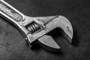 Old adjustable wrench on a black background. Black and white photograph of a working tool. old...