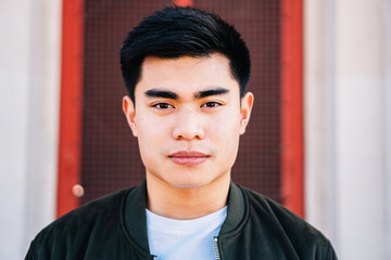 Portrait of serious asian guy looking at camera outdoors.