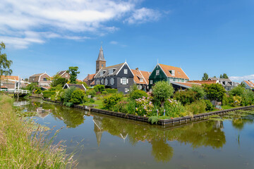 Fototapeta na wymiar Small town village of Marken with architecture traditional houses and church under blue sky and white fluffy cloud, The municipality of Waterland in the province of North Holland, Netherlands.