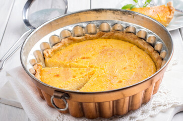 Traditional French tart au citron cake served as close-up copper backing form on a wooden table
