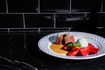 Baking with caramel inside, powdered sugar, strawberries, a scoop of ice cream, mint and violet petals