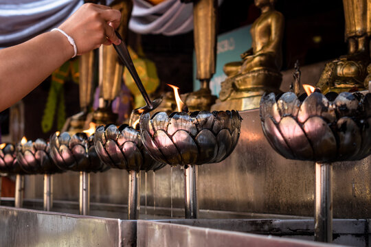Velas de aceite siendo encendidas por devotos, en templo budista de Tailandia