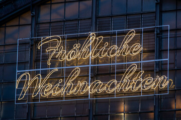 neon lettering in german merry christmas on a glass facade