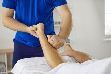 Masseur massaging patient's leg. Professional physiotherapist, osteopath, massagist, or...