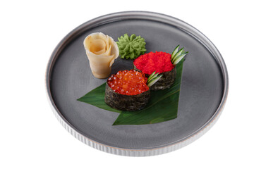 Roll with red salmon caviar, flying fish caviar, cucumber, nori on a banana leaf