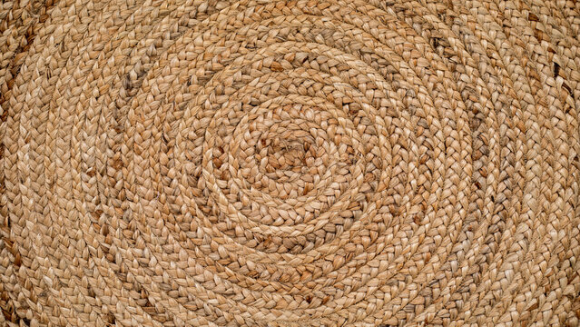 Round natural raffia rug with a spiral braided design and concentric circles that creates an ideal texture for backgrounds and graphic resources.
