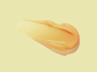 Lip balm orange colored texture smudge on peach red background - obrazy, fototapety, plakaty