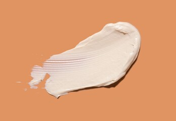 Cosmetic white mask or cleanser texture smudge swatch foam on peach orange background