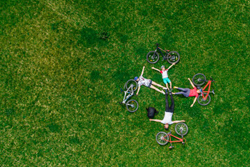 family cycling on bikes outdoors. aerial view from above. happy active parents with child have fun on the grass