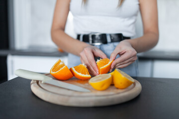 Woman peeling orange in the kitchen