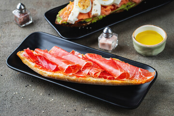 Traditional Spanish breakfast. Tostada with different toppings on a dark background