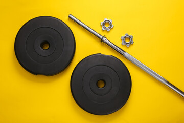 Disassembled barbell on yellow background. Bodybuilding and fitness. Top view