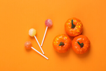 Trick or treat. Pumpkins with lollipops on orange background. Halloween concept