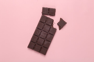 Broken chocolate bar on pink background