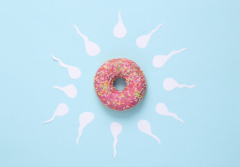 Allegory of fertilization of the egg. Donut with spermatozoa on blue background. Minimal creative still life - obrazy, fototapety, plakaty