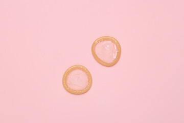 Two condoms on a pink background