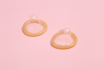 Two condoms on a pink background