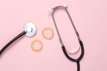 Treatment and prevention of men's health concept. Stethoscope with condoms on pink background