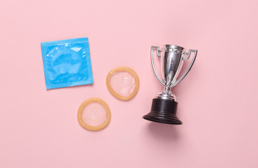 Macho, alpha male. Condoms with winner cup on pink pastel background